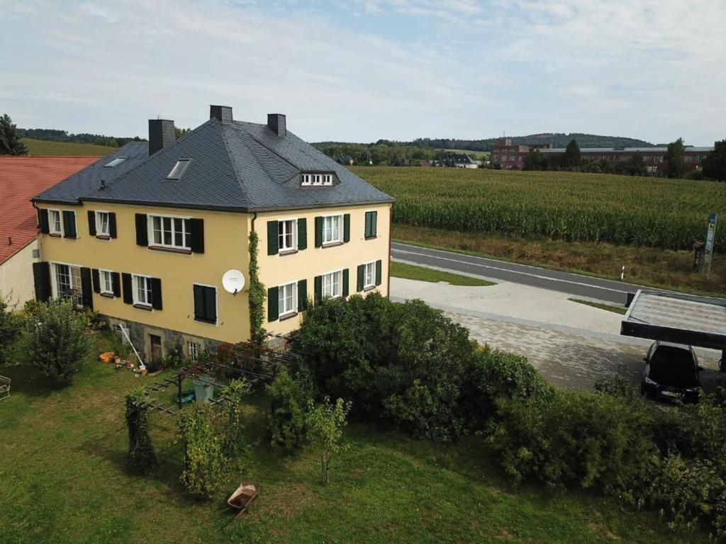 a yellow house with a black roof next to a road at Genesungsort Landhaus Dammert in Oppach