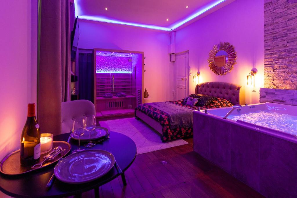Cette chambre violette comprend une baignoire et un lit. dans l'établissement Spa Edelweiss, à Dijon