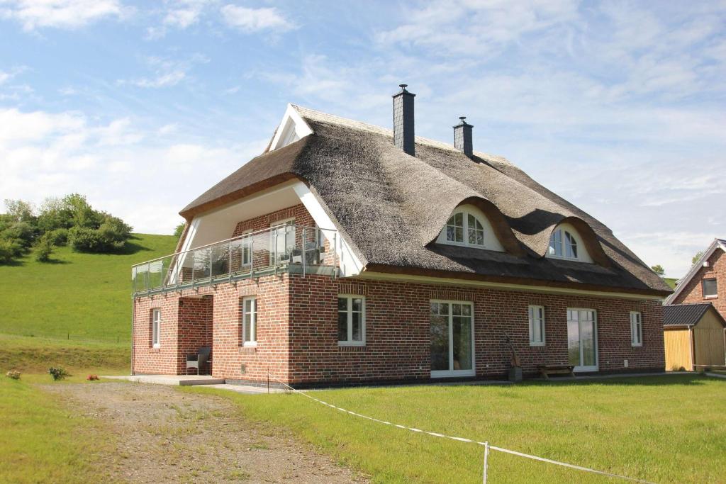 una casa con techo de paja en un campo en wassernahes Ferienhaus mit Meerblick in ruhiger Lage - Ferienhaus Rohrweihe en Gager