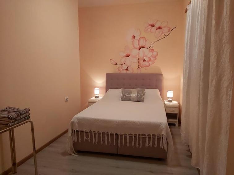 ein Schlafzimmer mit einem Bett mit einem Blumenbild an der Wand in der Unterkunft Sobe Apartmani Svitlana in Sukošan
