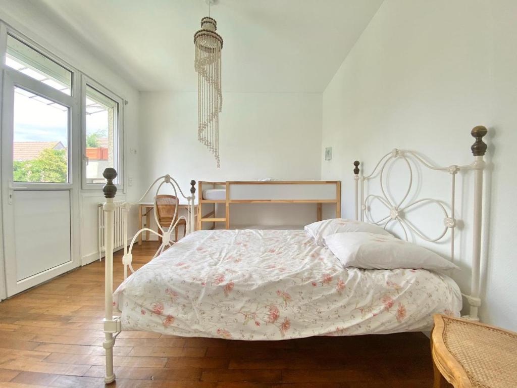 a white bedroom with a bed and a window at La Petite Coccinelle in Noisy-le-Grand