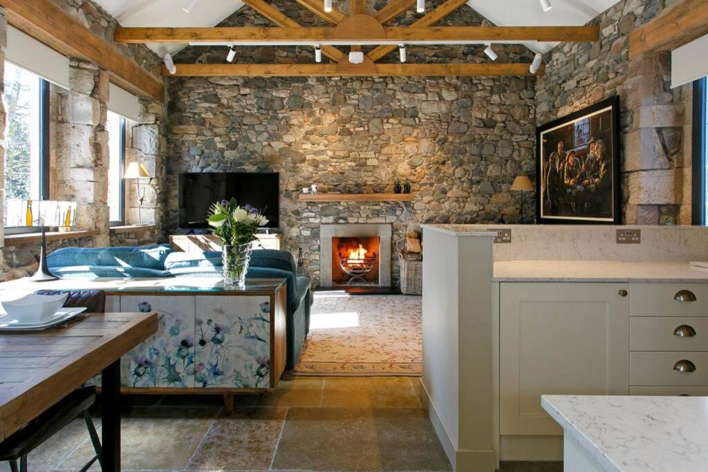 Laundry Cottage, River Doon fishing في آير: غرفة معيشة مع جدار حجري ومدفأة