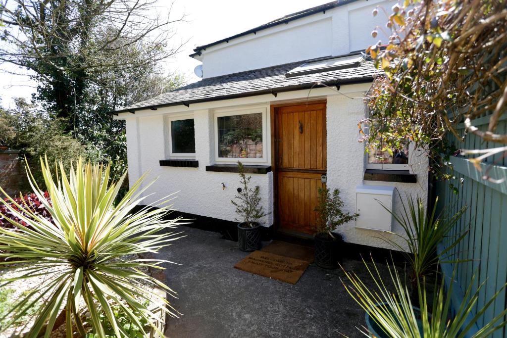 a small white tiny house with a wooden door at Mackerel Cottage in Budleigh Salterton