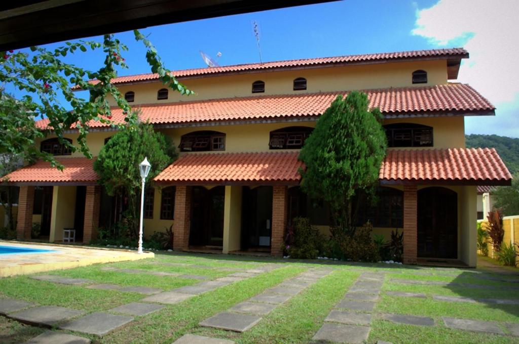 une maison avec une cour devant elle dans l'établissement Chalé Massaguaçu, à Caraguatatuba