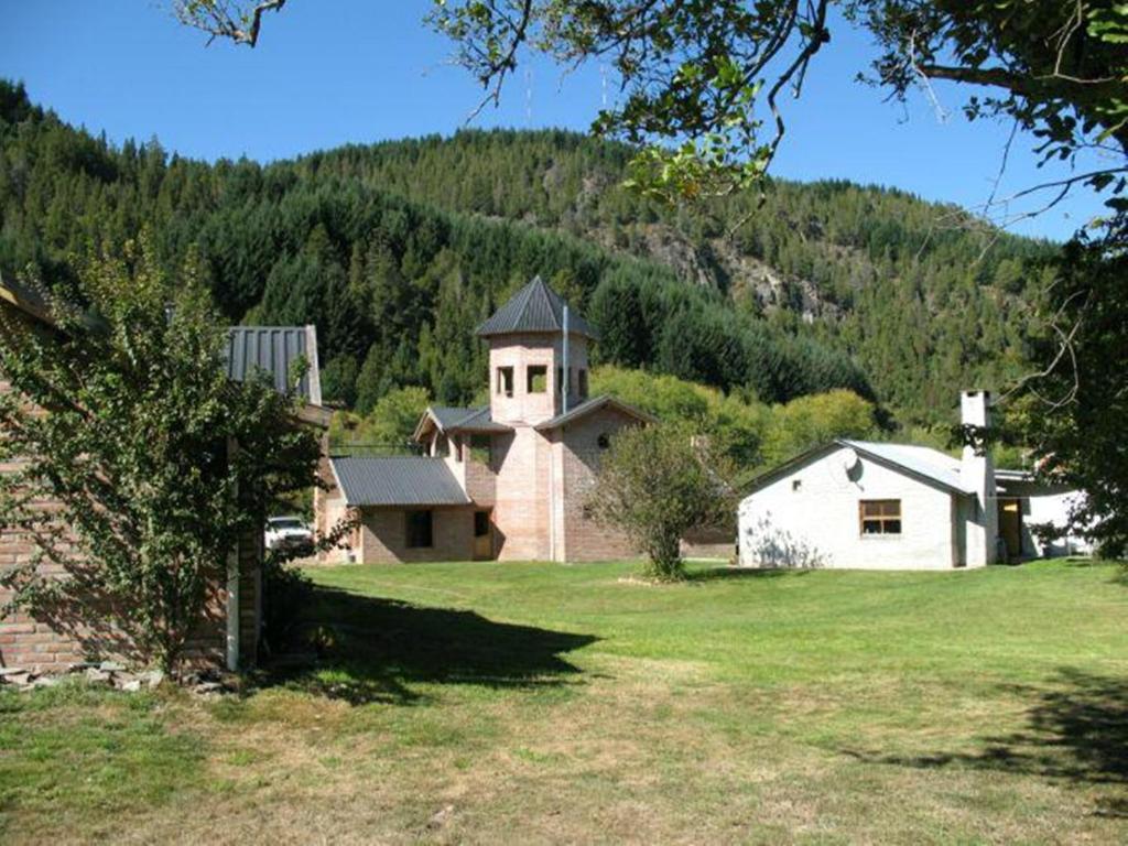 a house in a field with a mountain in the background at Hosteria Tres Picos in Lago Puelo