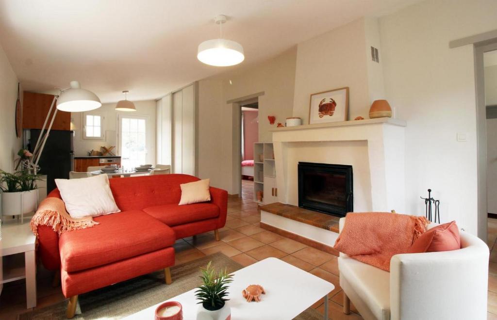 - un salon avec un canapé rouge et une cheminée dans l'établissement Domaine du Flamand - Gîtes du Pin Sec côté OCEAN, à Naujac-sur-Mer