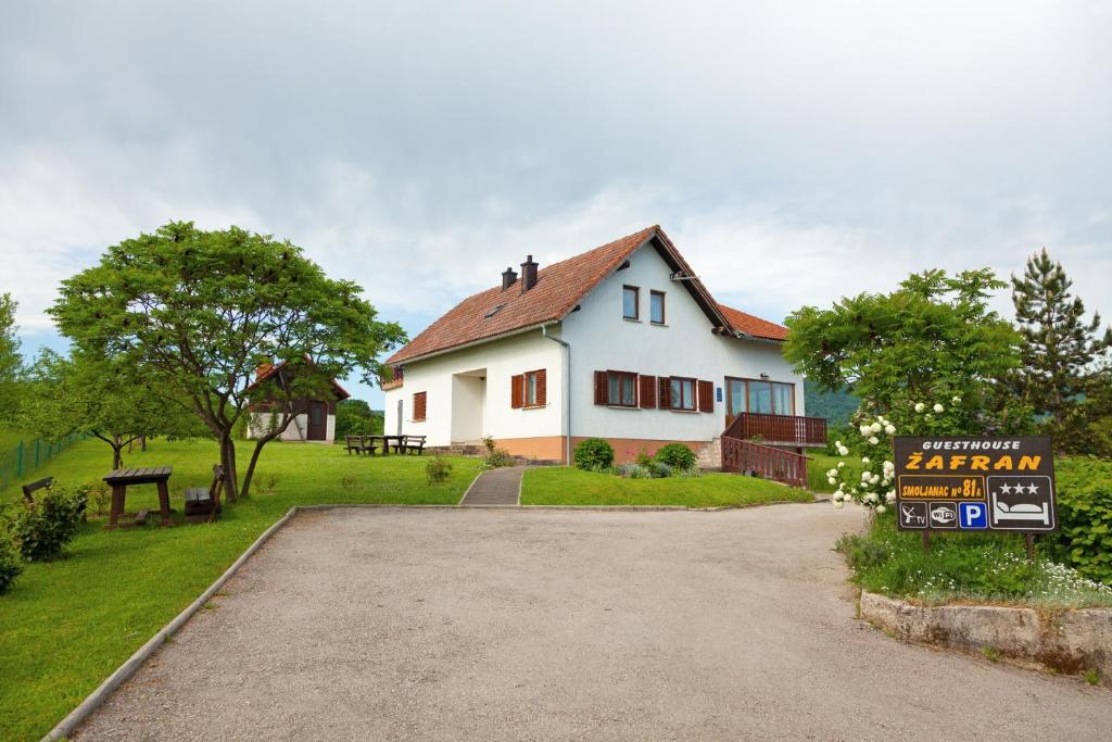 une maison blanche avec un panneau devant elle dans l'établissement Guesthouse Zafran, à Smoljanac