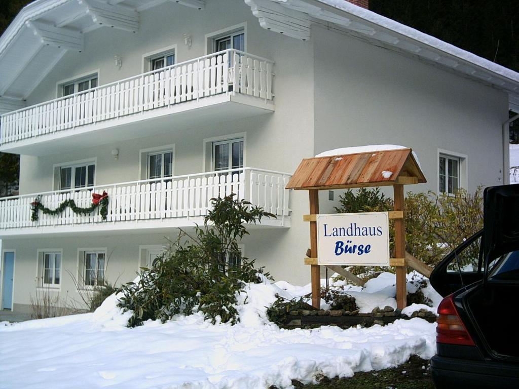 Un grand bâtiment blanc avec un panneau dans la neige dans l'établissement Landhaus Bürse, à Flattach