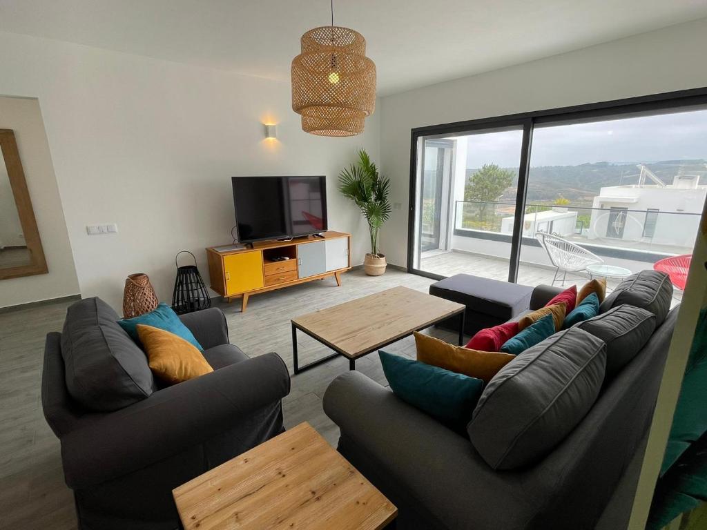 ein Wohnzimmer mit Sofas, einem TV und einem Tisch in der Unterkunft Cairnvillas: Villa Terra C39 - Luxury Villa with Private Swimming Pool near Beach in Aljezur