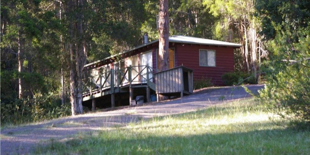 a small cabin with a bridge in the woods at Orana"Welcome" Cabin in The Tops in Bandon Grove