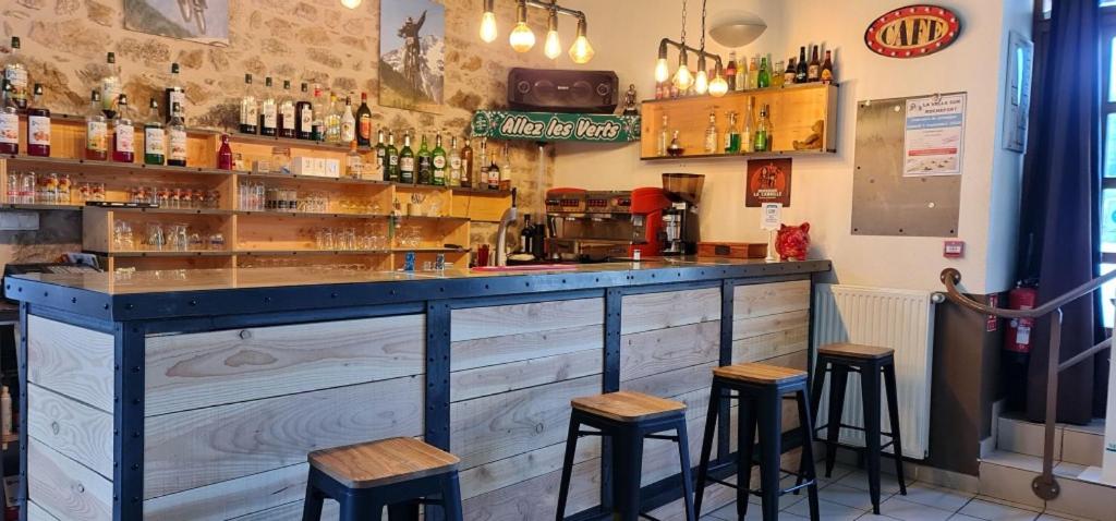 un bar con taburetes de madera en un restaurante en L'auberge De La Source en La Valla