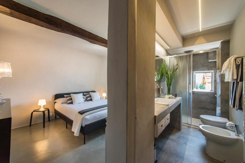 ein Schlafzimmer mit einem Bett und ein Badezimmer mit einem Waschbecken in der Unterkunft Palazzo del Papa Country Suites in Siena