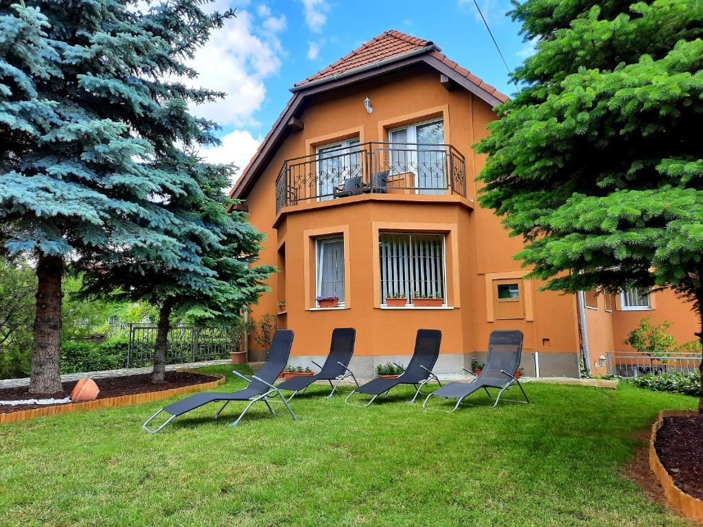 a group of chairs sitting in the grass in front of a house at Harmónia Vendégház in Balatonalmádi