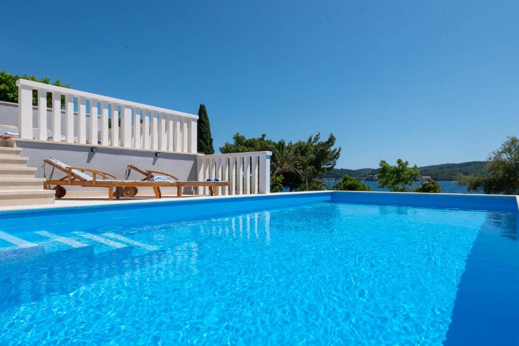 a blue swimming pool with a bench next to a house at Holiday Villa Sasha in Kučište