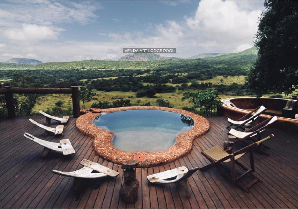 a pool with lounge chairs on a deck with a view at Leshiba Wilderness in Louis Trichardt