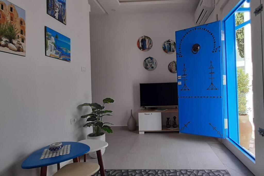 a living room with a blue door and a tv at Bolbol in Dar Salah Bey