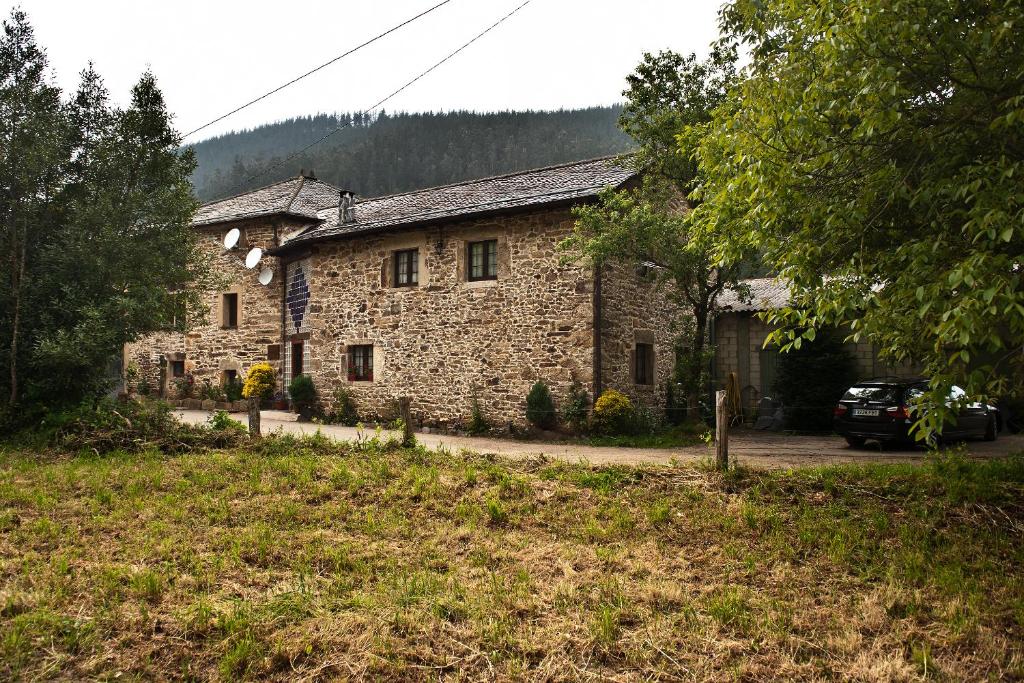 a stone house with a car parked in front of it at Casa Rural Madreselva 1 in Navelgas