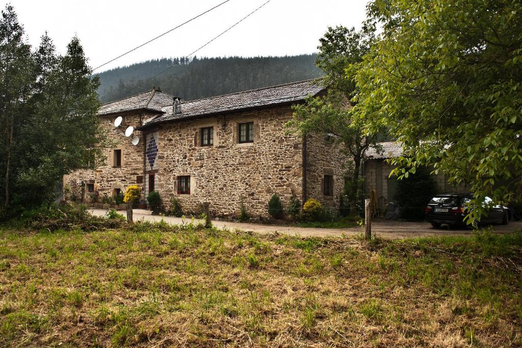 una casa de piedra con un coche aparcado delante de ella en Casa Rural Madreselva, en Navelgas