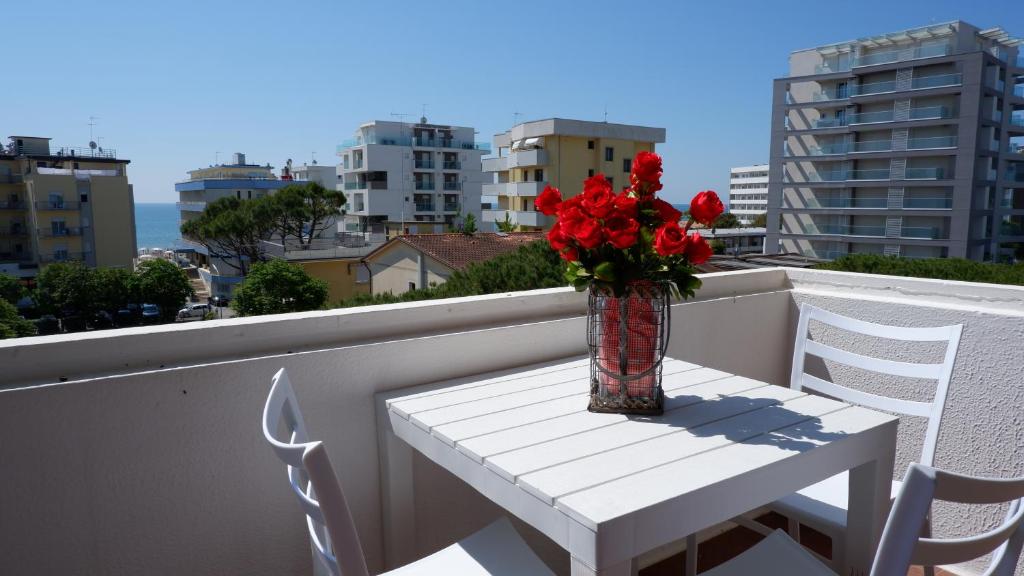 um vaso de flores vermelhas sobre uma mesa na varanda em APPARTAMENTO SAN MARCO em Lido di Jesolo