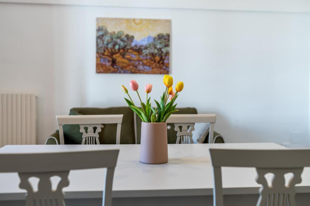 eine Vase mit Blumen auf einem Tisch mit zwei Stühlen in der Unterkunft IL GIARDINO DEL MANDARINO HOUSE in Montalbano