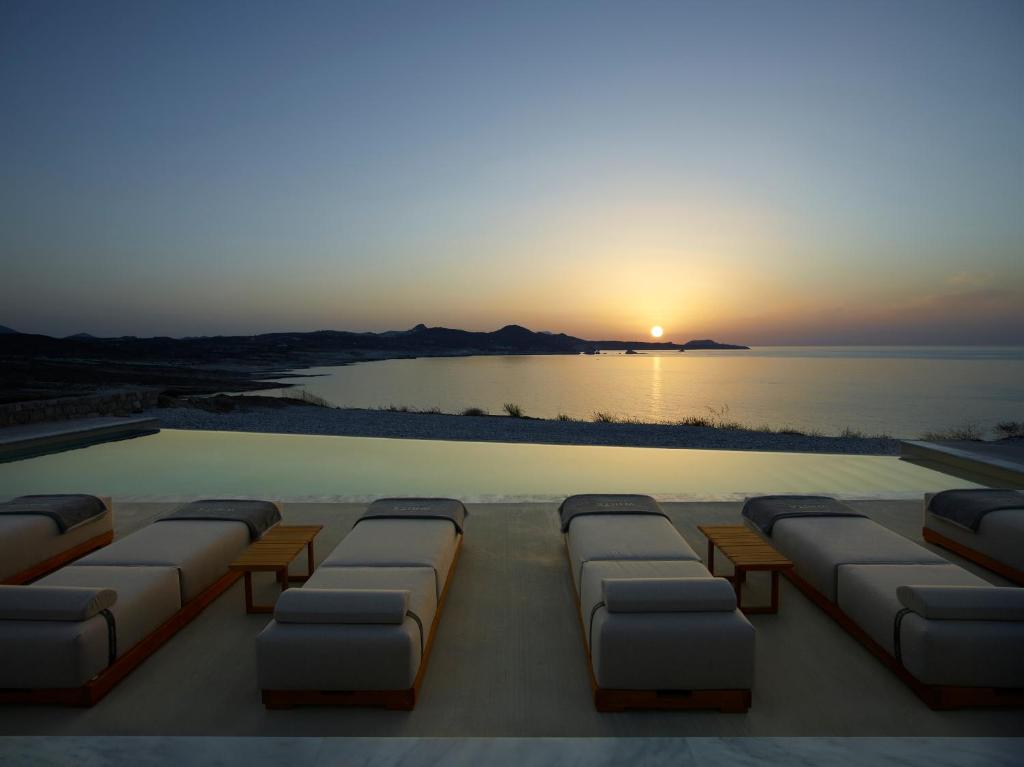 a swimming pool with a sunset in the background at Domes White Coast Milos, Adults Only - Small Luxury Hotels of the World in Mytakas