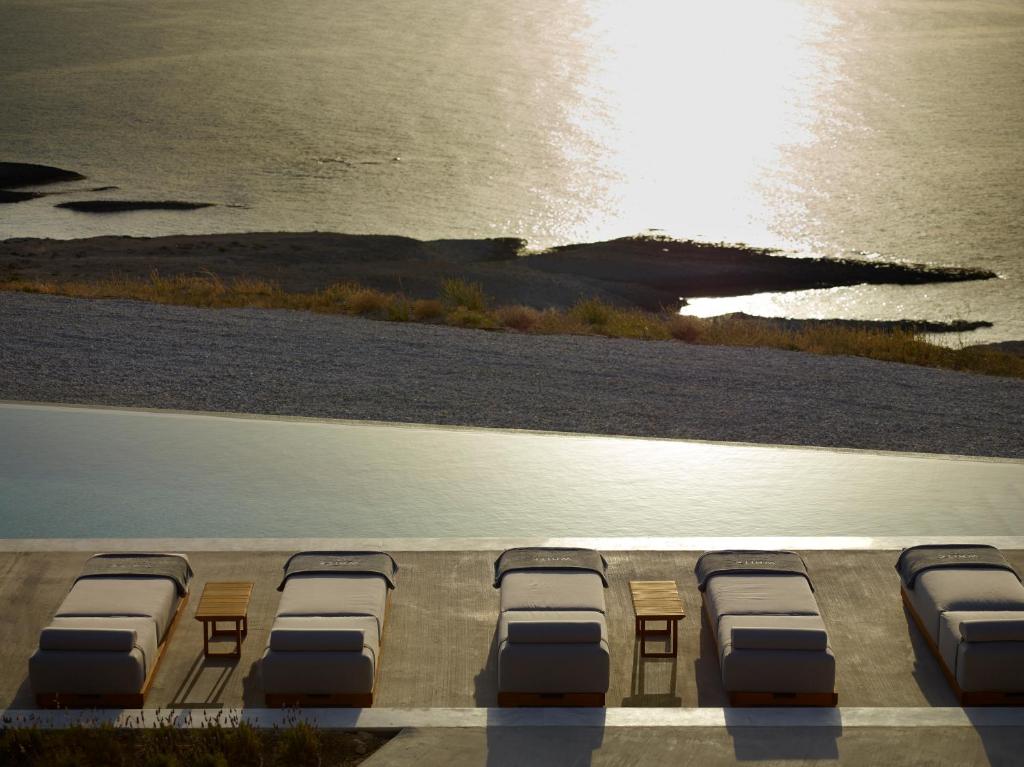 a row of beds on a beach with the ocean at Domes White Coast Milos, Adults Only - Small Luxury Hotels of the World in Mytakas