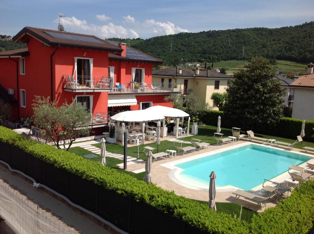 a swimming pool in front of a red house at G&G Bed&Breakfast and apartments in Garda