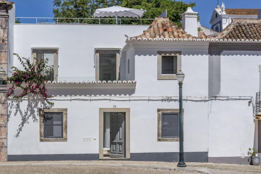une maison blanche avec un éclairage de rue devant elle dans l'établissement Casa Trindade, encanto no coração de Tavira, à Tavira
