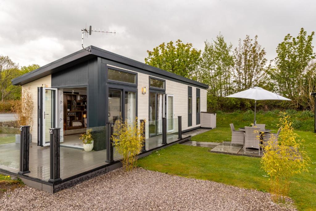 ein kleines schwarzweißes Haus mit einer Terrasse in der Unterkunft Inside No 1 Retreat Carnforth in Carnforth