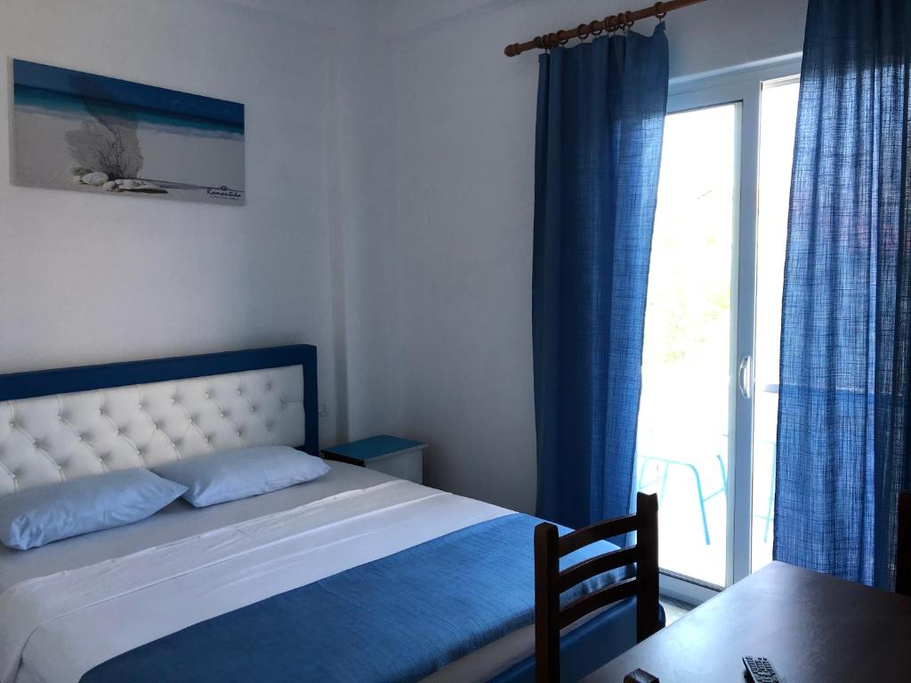 a bedroom with a bed with blue curtains and a window at Romantika in Shëngjin