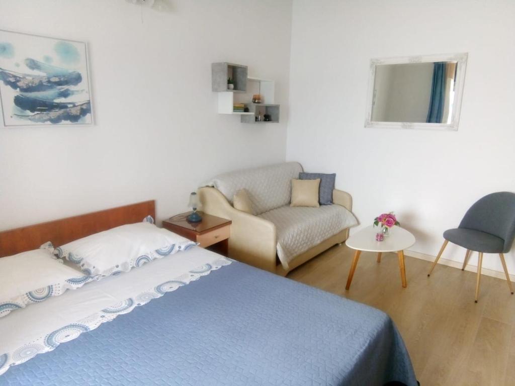 a bedroom with a bed and a chair at Apartments and Rooms Nikša in Podgora