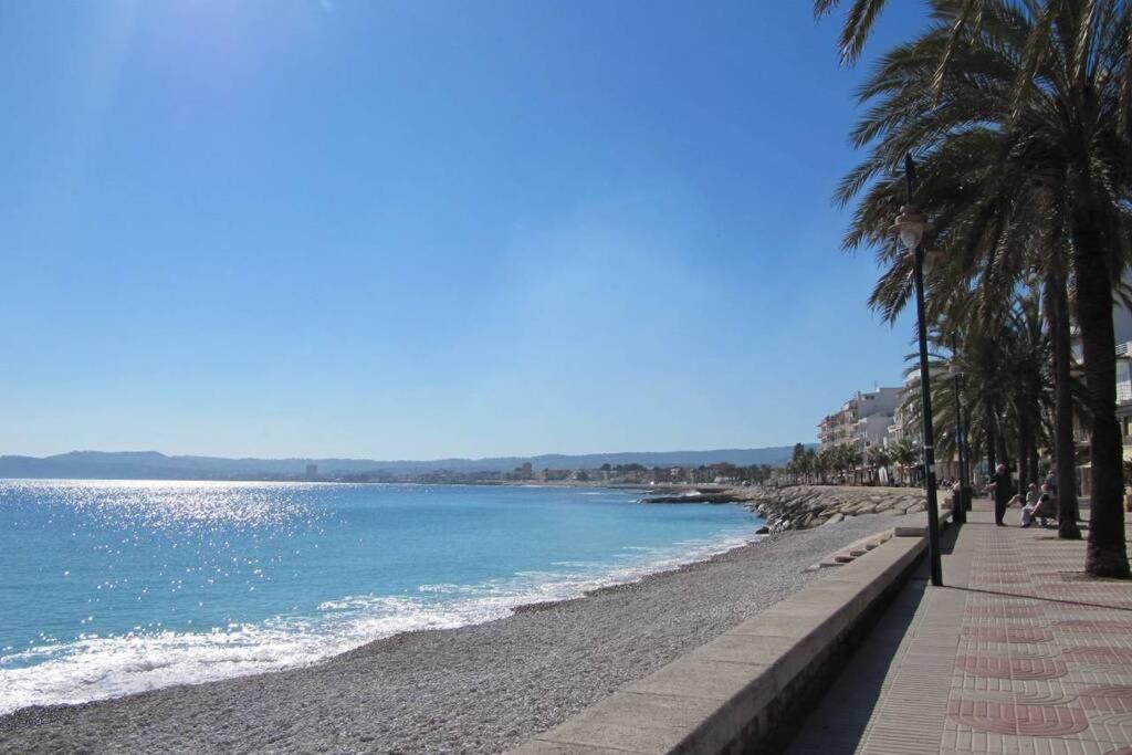 a beach with palm trees next to the water at La Gaviota apartment, in the heart of the port in Jávea