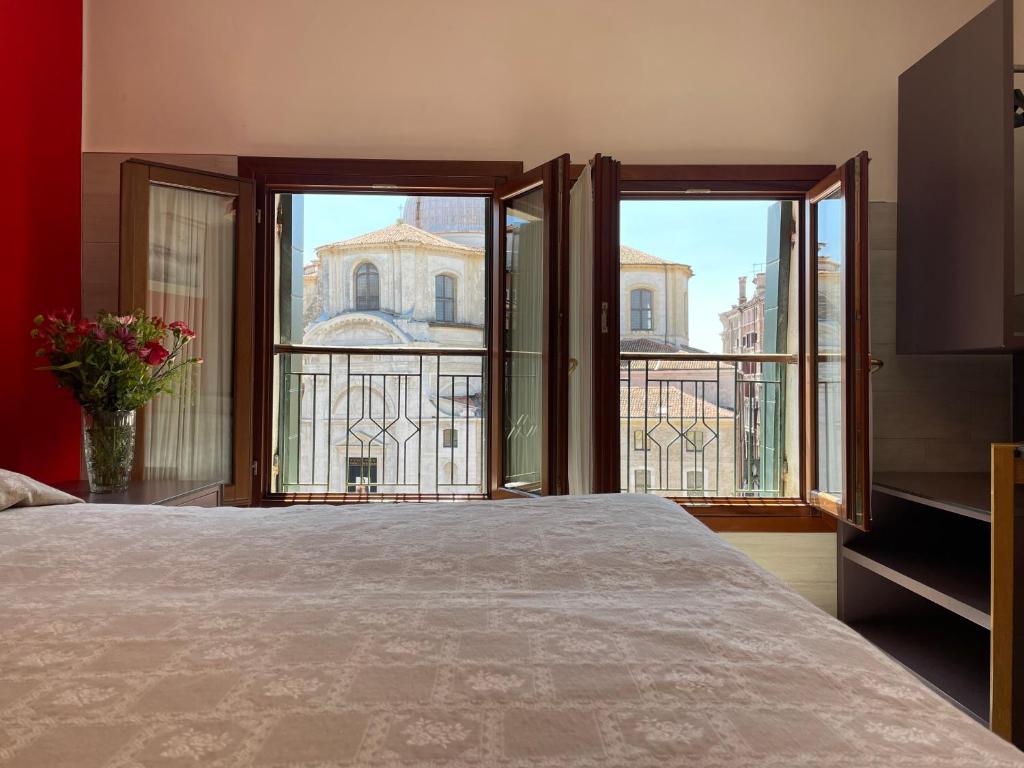 a bedroom with a large bed and large windows at Hotel San Geremia in Venice