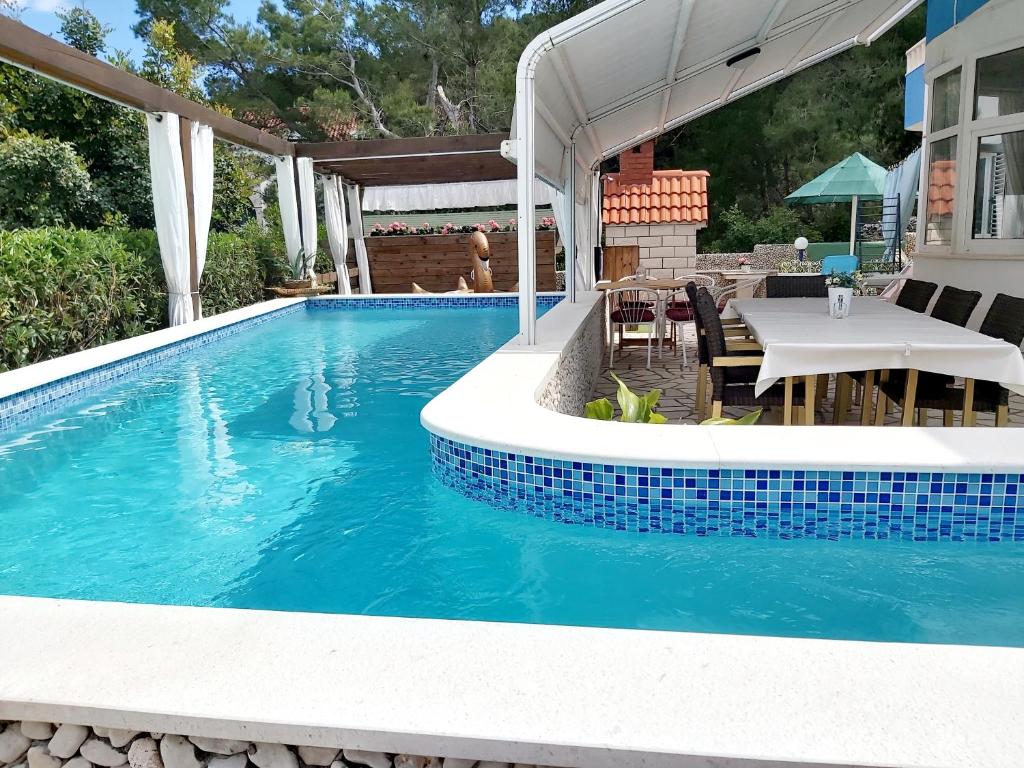 a swimming pool with a table and a table and a swimming pool at Villa Kale Apartments in Slatine
