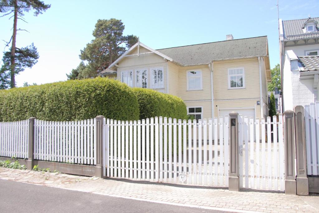 una cerca blanca frente a una casa en Family Apartments en Jūrmala