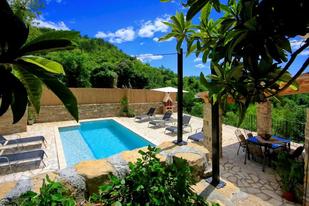 a pool in a garden with chairs and a table at Villa Alba in Livade