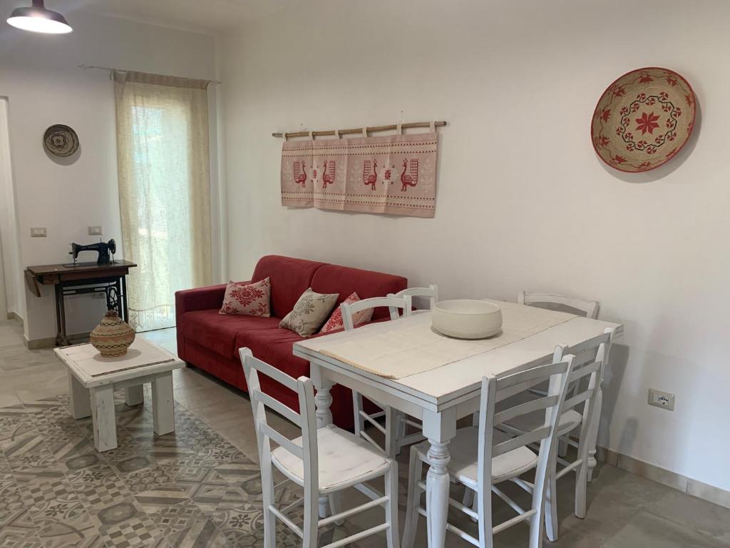 een woonkamer met een rode bank en een tafel en stoelen bij Sa Domo ‘e su Banditore in Orosei