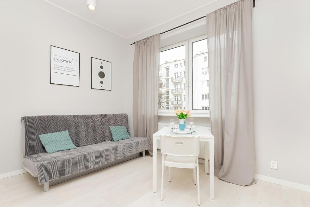 a white living room with a table and a couch at Apartments Gdynia Abrahama in Gdynia