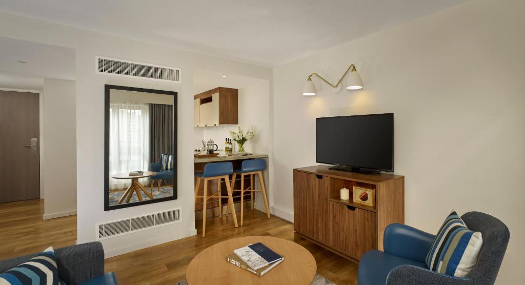 a living room with a television and a table at Citadines Barbican London in London