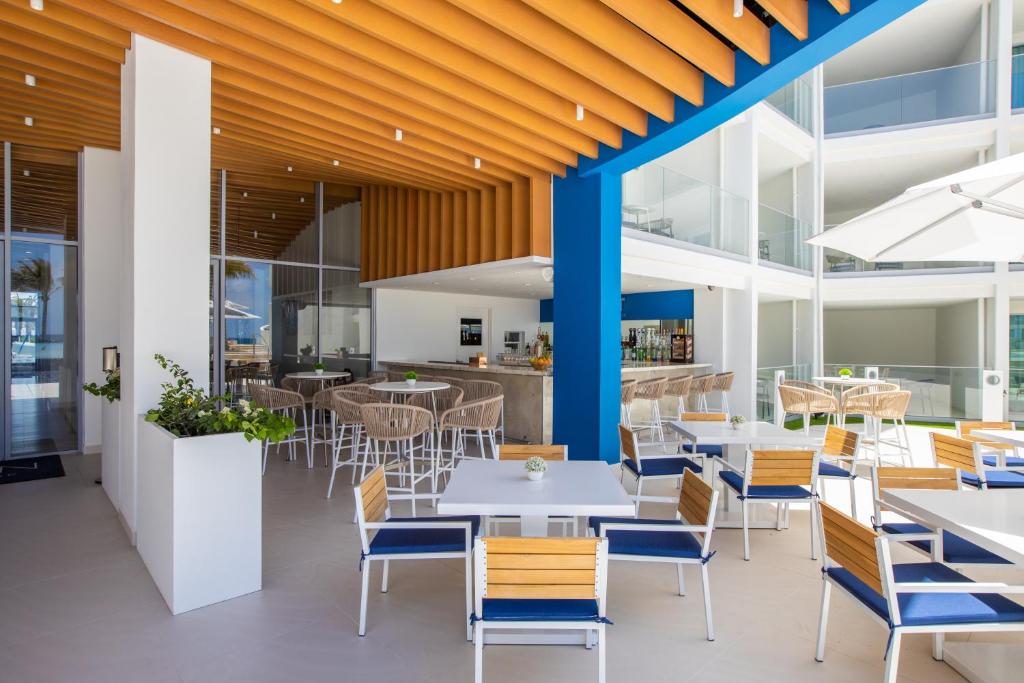 a restaurant with white tables and blue chairs at The Morgan Resort Spa & Village in Simpson Bay