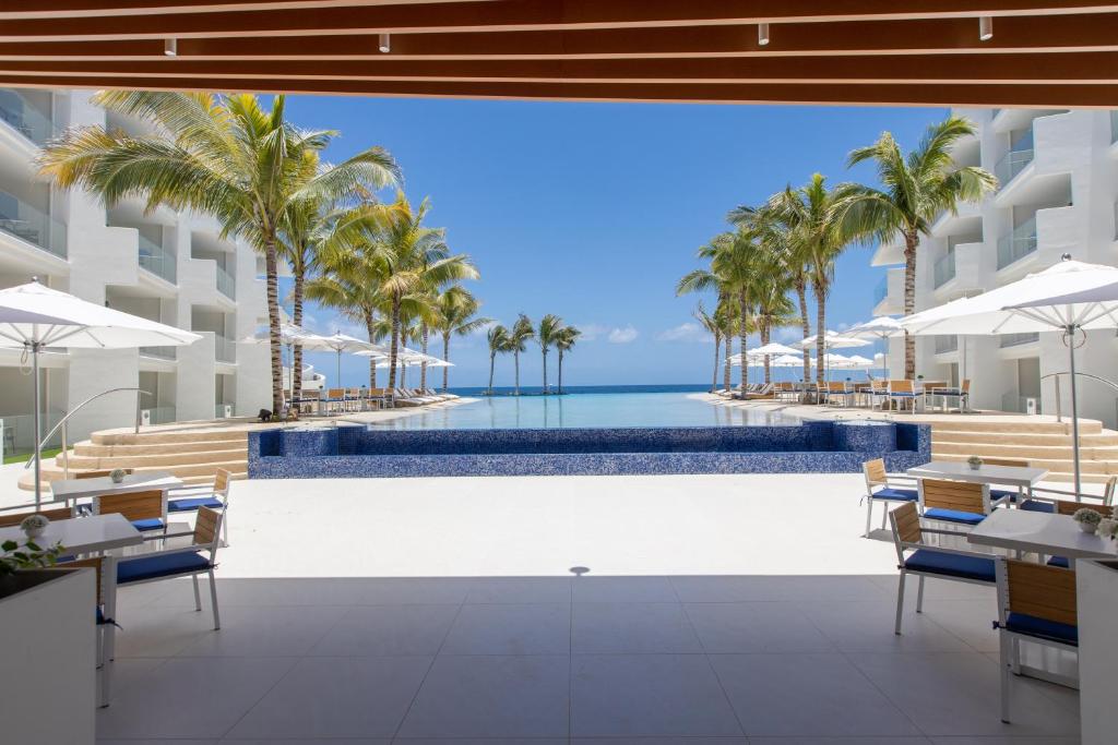 an image of a resort pool with palm trees and the ocean at The Morgan Resort Spa & Village in Simpson Bay