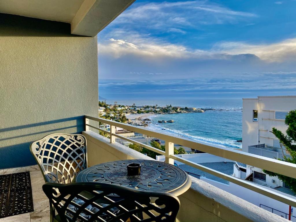 Clifton YOLO Spaces - Clifton Beachfront Executive Apartment في كيب تاون: طاولة وكراسي على شرفة مطلة على المحيط