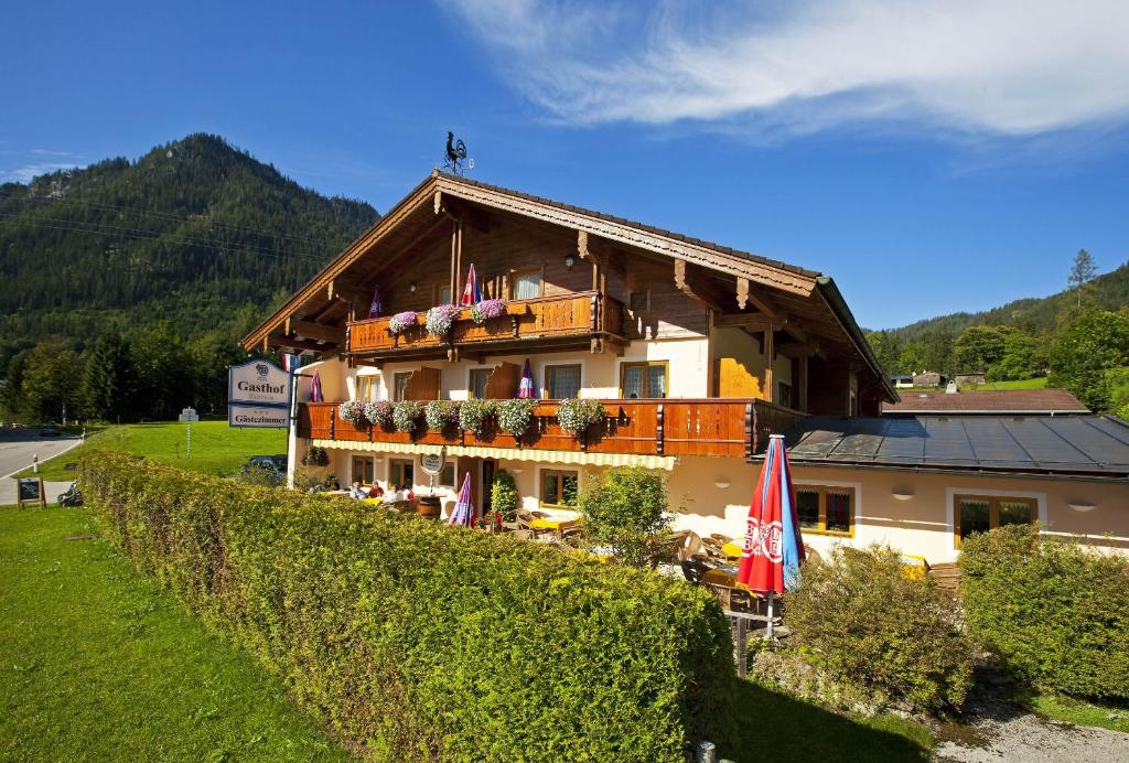 un edificio con balcón con mesas y sombrillas en Gästehaus Baltram, en Ramsau