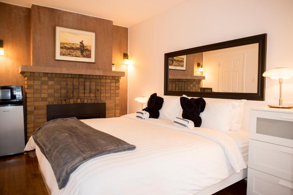 a bedroom with a large white bed with a fireplace at Auberge Hotel Spa Watel in Sainte-Agathe-des-Monts