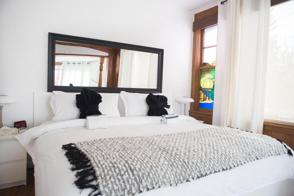 a bedroom with a large white bed with a large mirror at Auberge Hotel Spa Watel in Sainte-Agathe-des-Monts