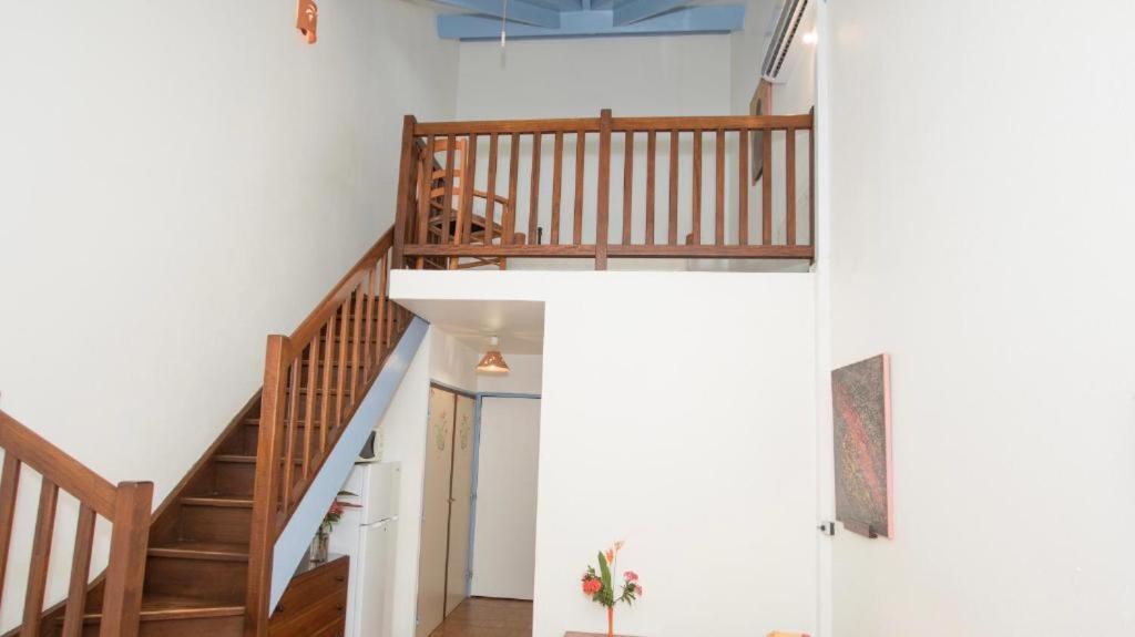 - un escalier dans une maison dotée de murs blancs et de parquet dans l'établissement Appartement Paradis, à Sainte-Anne