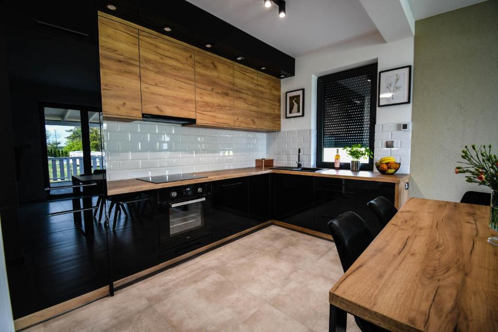 a kitchen with black cabinets and a wooden table at Apartament Lawendowy in Mikołajki
