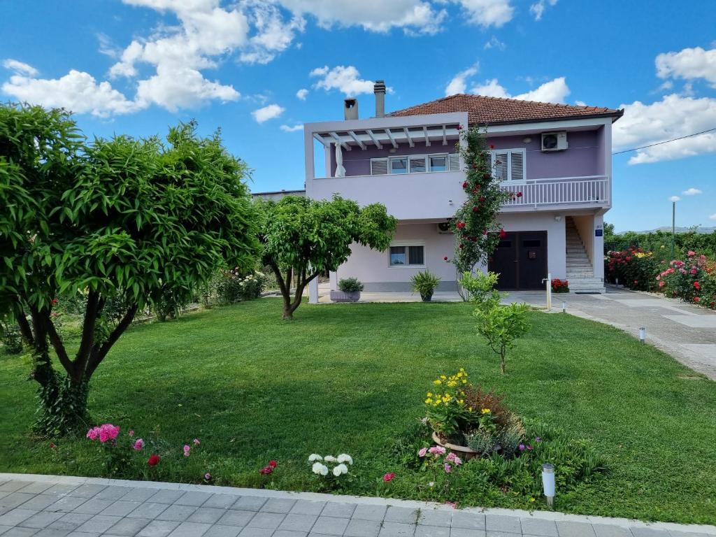 een huis met een tuin met bloemen bij Apartman Galov in Metković