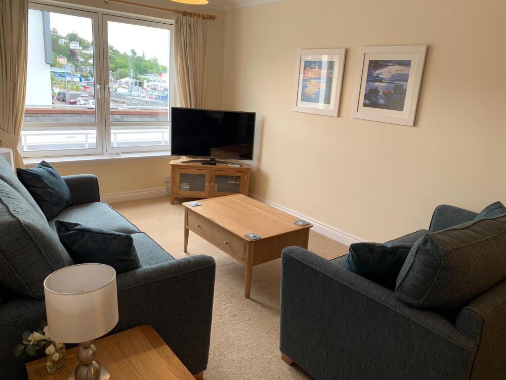 a living room with two couches and a tv at 1/5 Lismore House in Oban