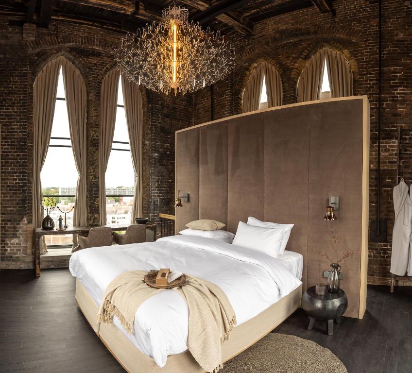 a bedroom with a large white bed with a chandelier at The Clock Tower in Weesp